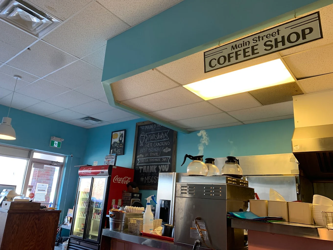 Inside Main Street Cafe with teal walls, local art, and the iconic COFFEE SHOP sign
